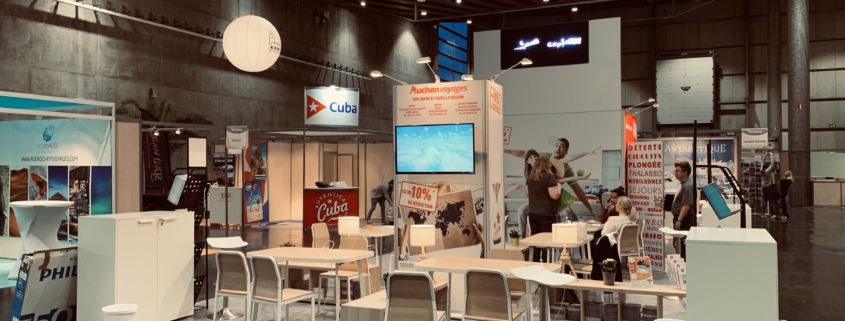 Conception et installation de stands pour foire et exposition. Salon Mahana Lyon 2020. Solution de stand Le Transversale avec impression de tissus tendus et enseignes hautes. Location de mobilier et de plantes thématiques. Hologrammes dédiés avec deux logos Auchan en lévitation