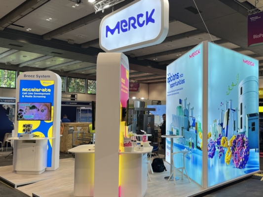 Stand Merck - BPI Hambourg 2025 Stand sur-mesure avec mobilier et cloisons rétro-éclairées personnalisées, plancher technique.